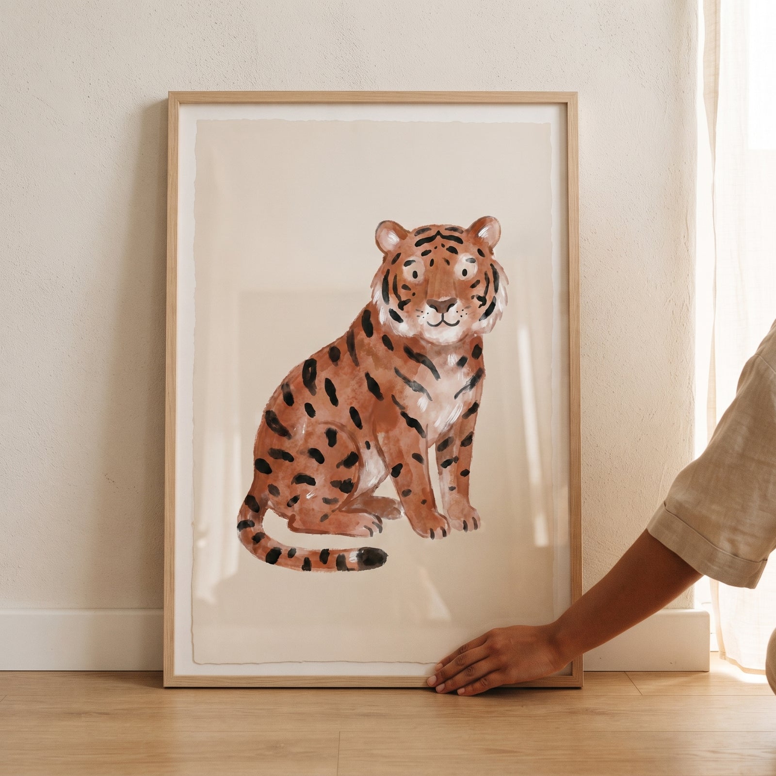 Watercolor rust spotted tiger wall art in a light wood frame rests on a floor against a neutral wall.