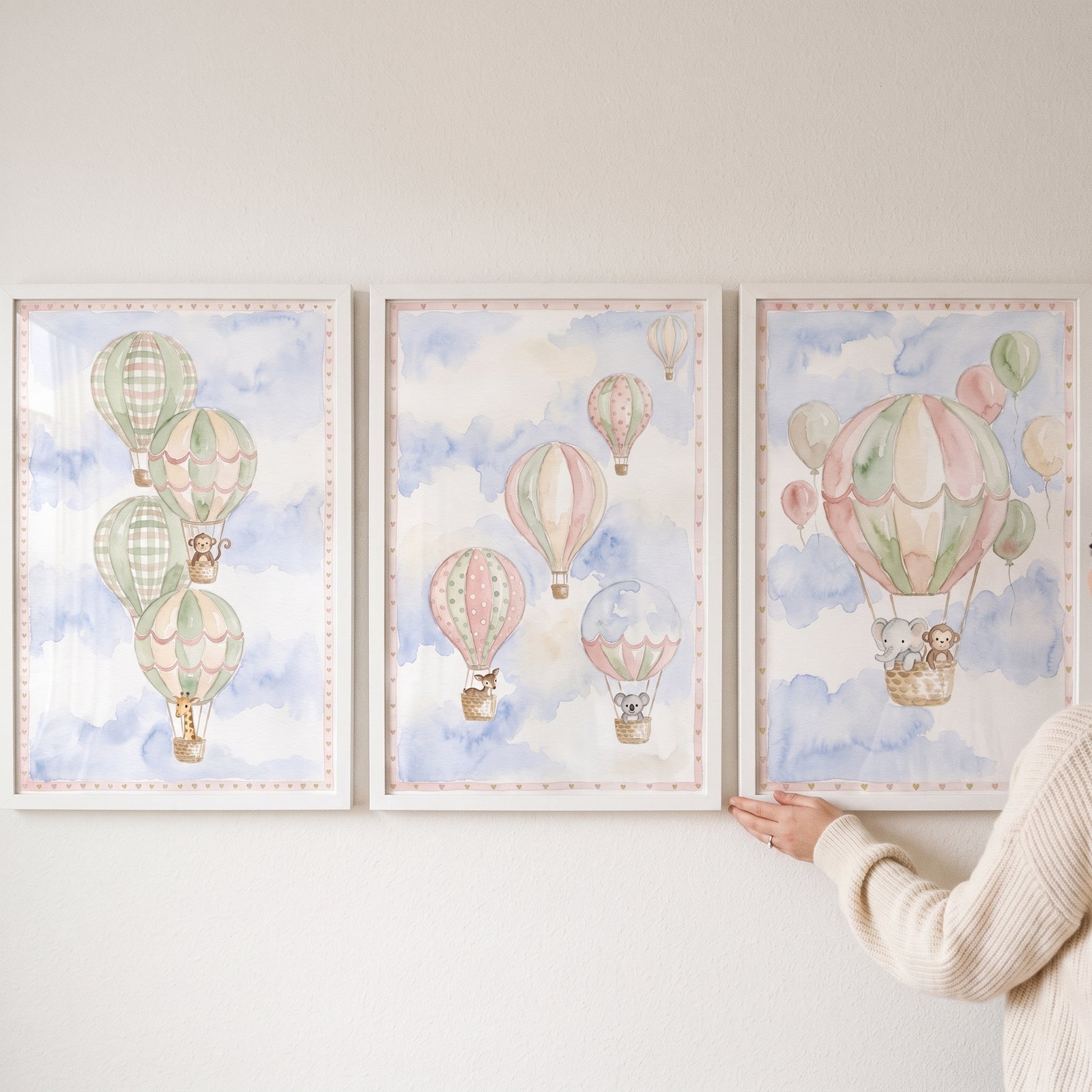 Watercolor safari animal balloon wall art set of 3 shows animals in hot air balloons floating among soft blue clouds.