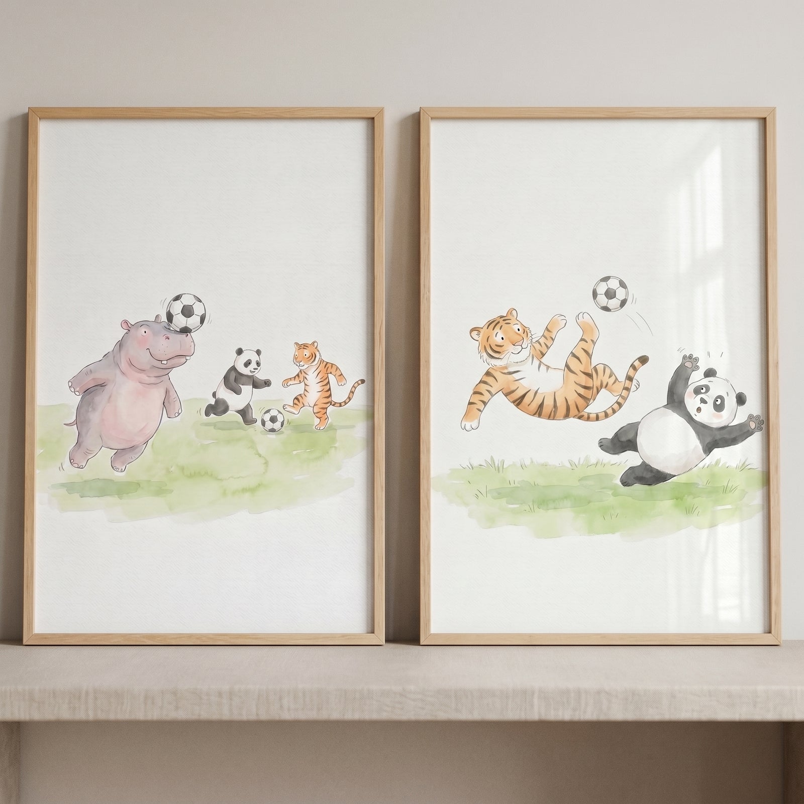 Watercolor soccer panda tiger wall art set of 2 shows a hippo, panda, and tiger playing soccer in light wood frames.