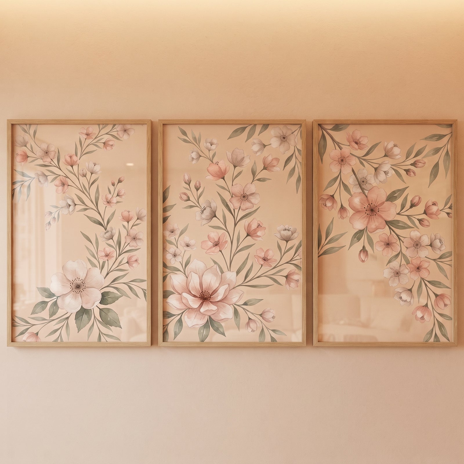 Watercolor soft peach floral wall art set of 3 with light wood frames hanging on a neutral wall.