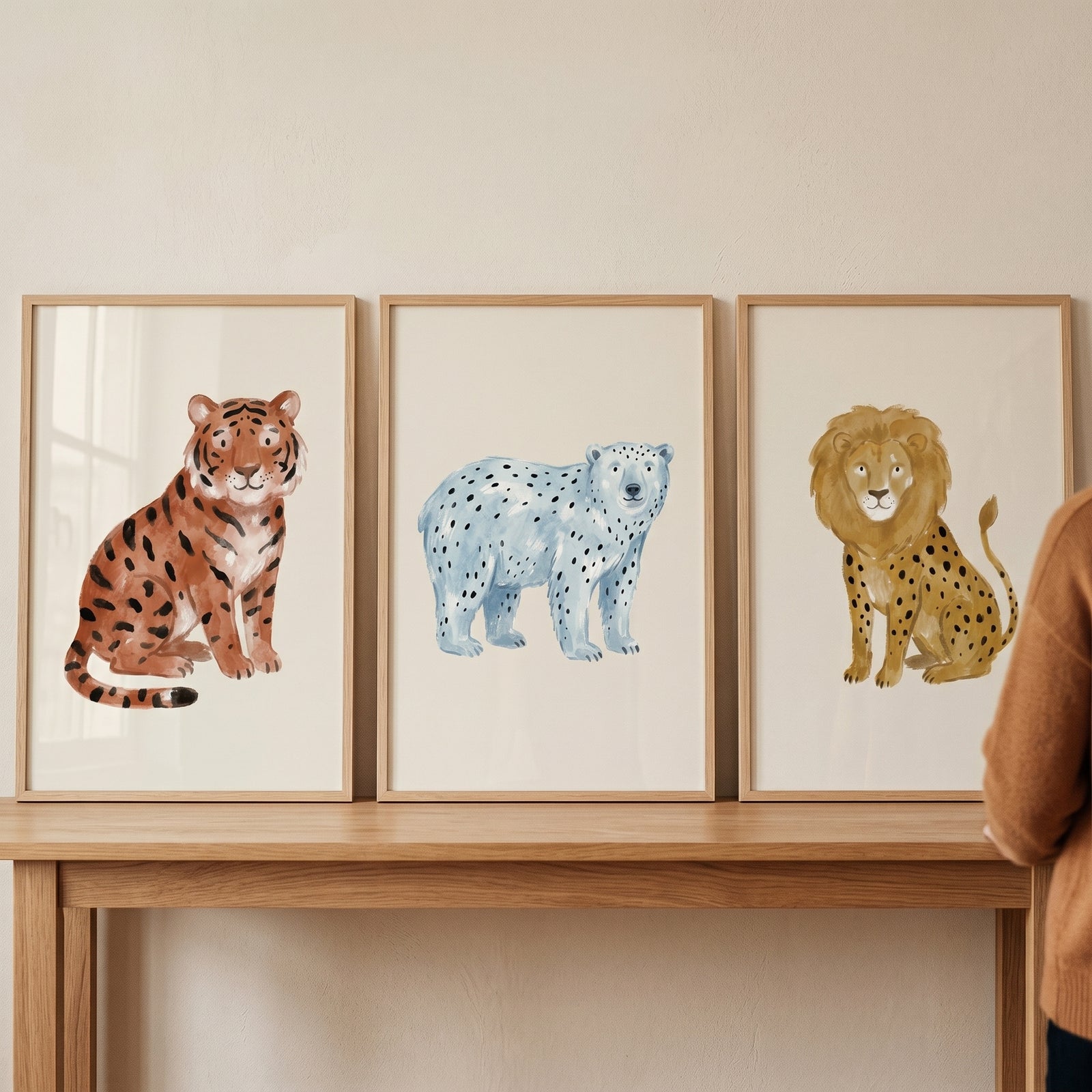 Watercolor spotted wild animals wall art set of 3 featuring a tiger, blue bear, and lion hybrid on a wooden table.