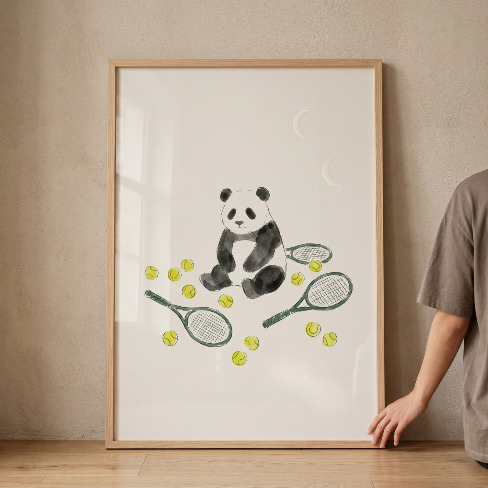 Watercolor tennis ball panda wall art shows a sitting panda surrounded by green rackets and yellow balls in a wood frame.