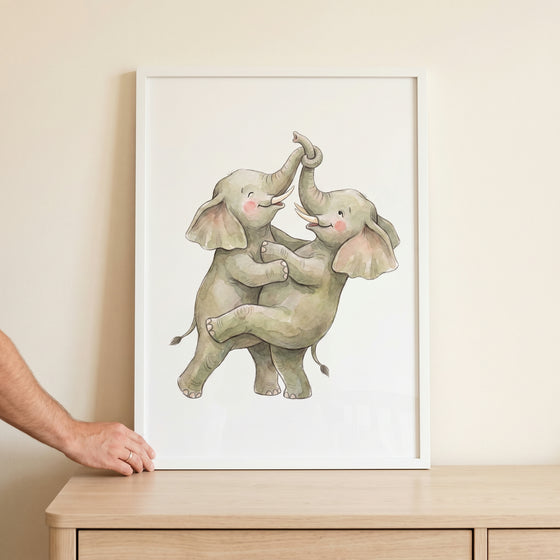 Two playful elephants hug with trunks intertwined in this watercolor trunk link elephant wall art inside a white frame.