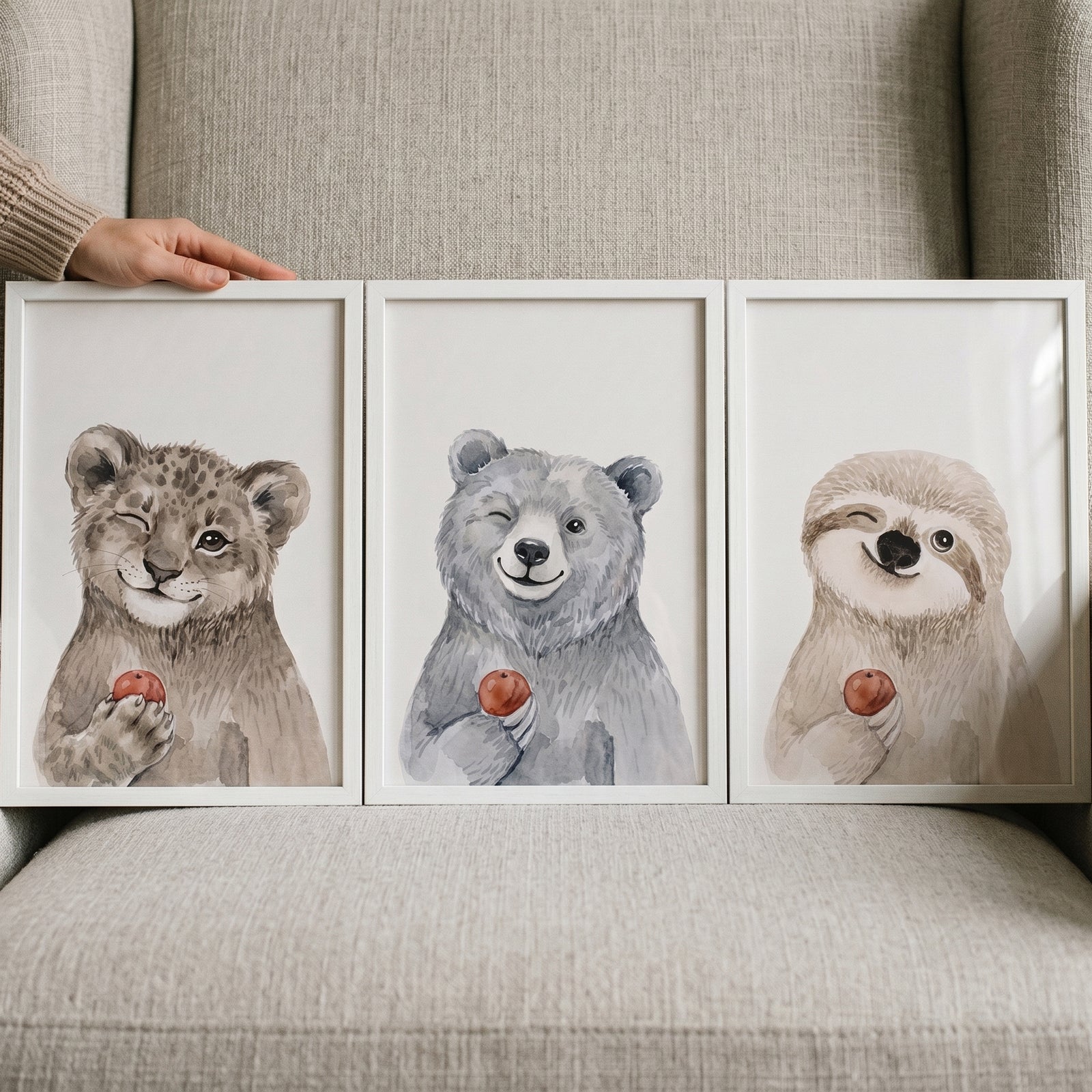 Watercolor winking baby animal wall art set of 3 featuring a leopard, bear, and sloth holding small red fruit.
