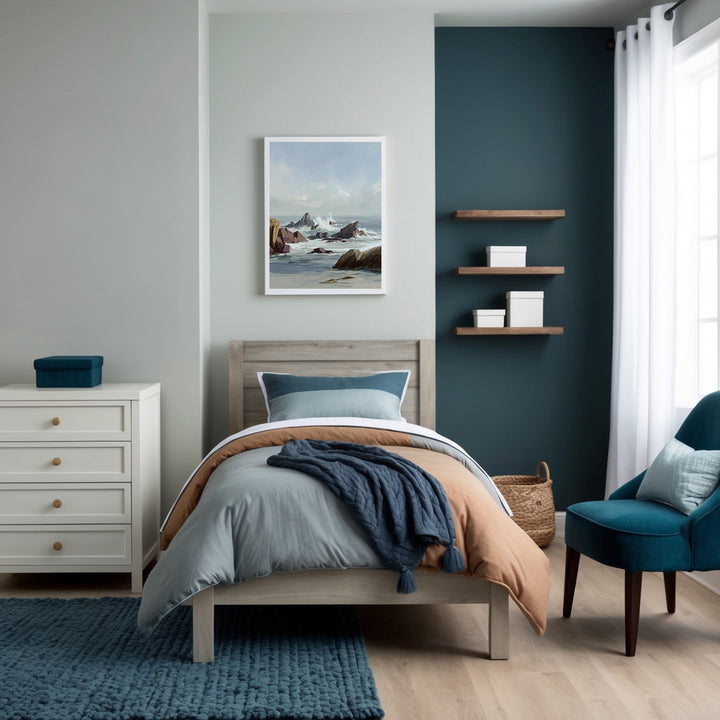 Contemporary bedroom styled in soothing blues, grays, and natural wood tones, creating a calming atmosphere. Above the bed, a framed painting of a rocky seascape with gentle waves and distant cliffs enhances the serene, ocean-inspired theme of the room.