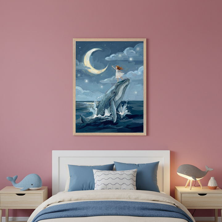 Kid's bedroom with pink walls. A white bed with blue and cream bedding sits between two light wood nightstands. A large framed painting hangs centered above the bed, depicting a blue whale breaching from dark water with a girl standing on its head, under a crescent moon and starry night sky in an illustration style.