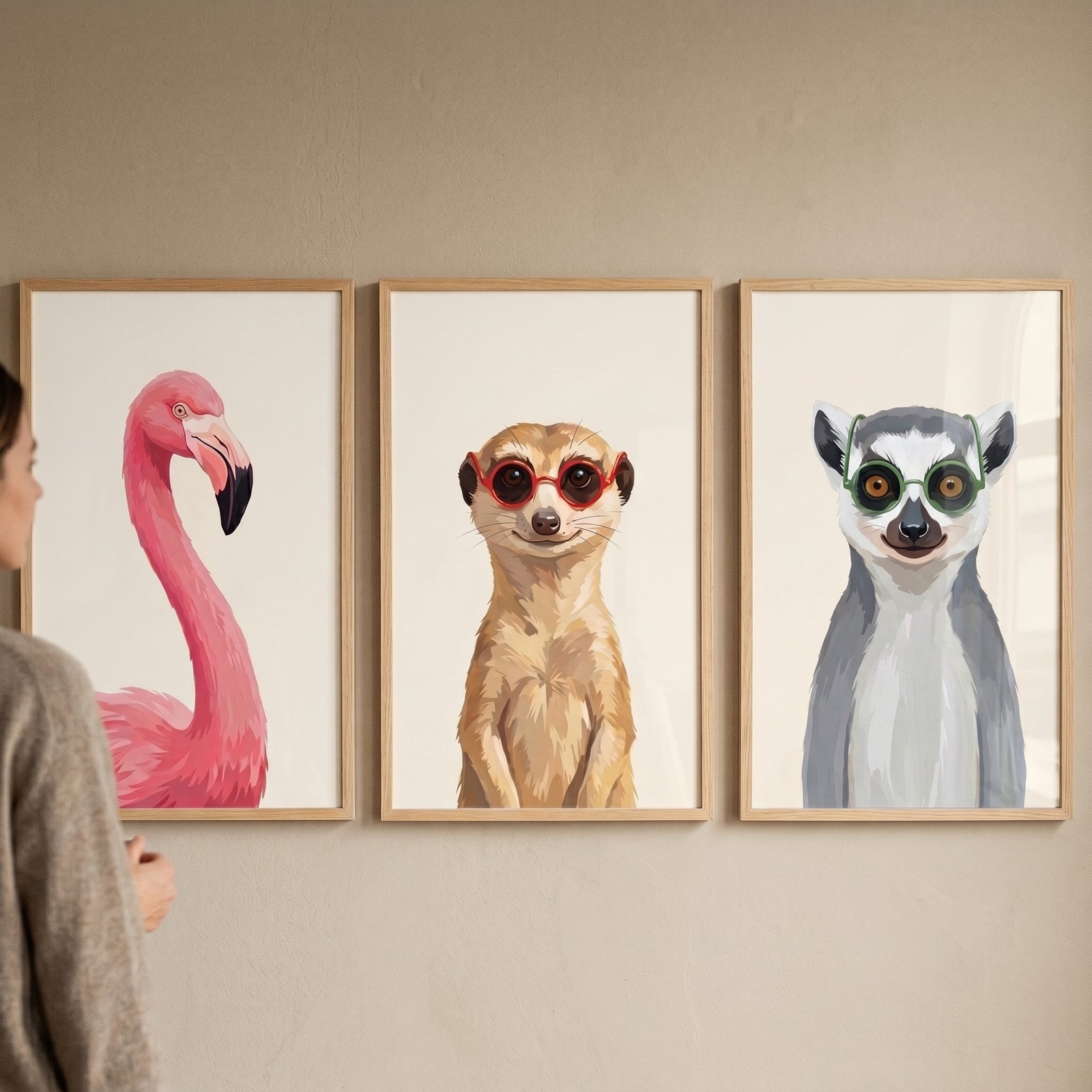 Woman views a whimsical accessorized safari animal wall art set of 3 with a flamingo, meerkat, and lemur in glasses.