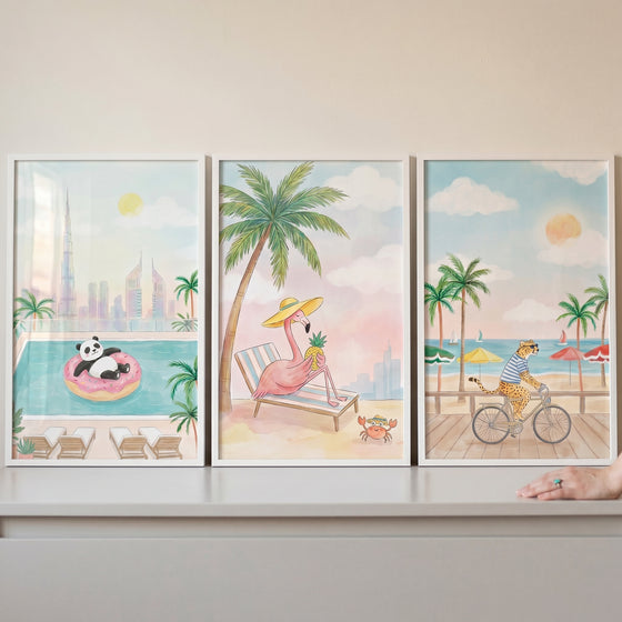 Whimsical animal wall art set of 3 featuring a panda in a pool, a flamingo on a beach, and a cheetah on a bicycle.