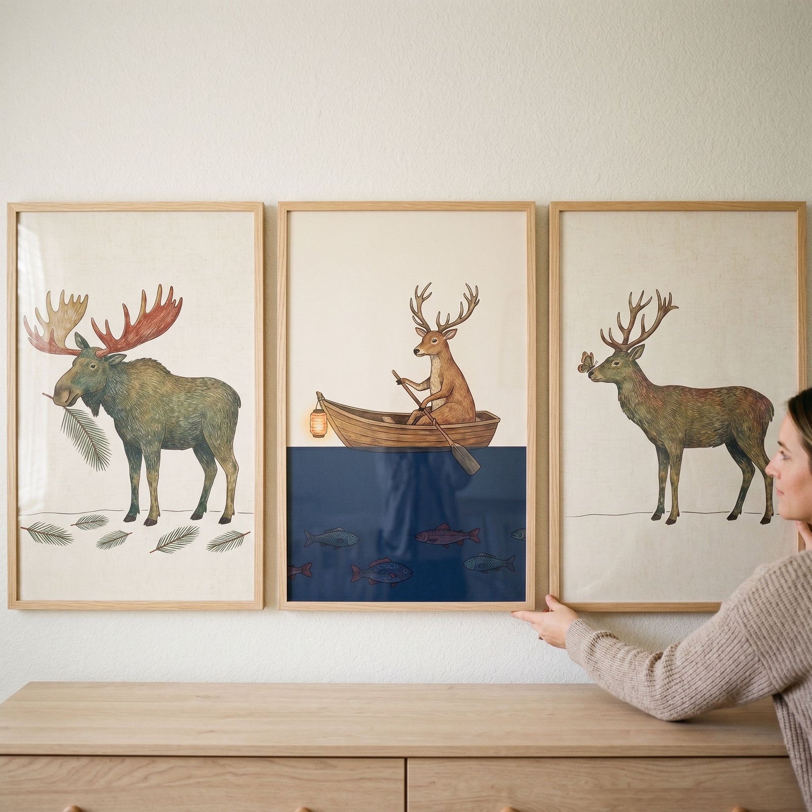 Whimsical antlered forest animals wall art set of 3 featuring a moose and deer, hung above a light wood dresser.