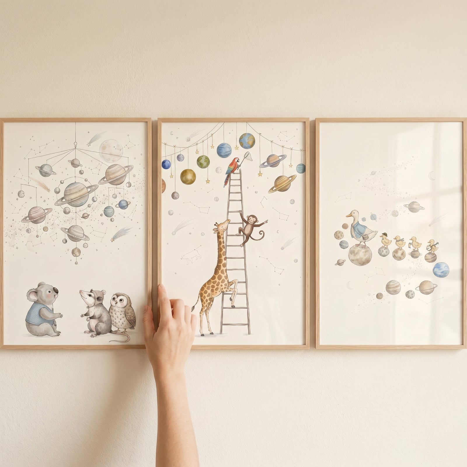Whimsical cosmic watercolor animals artwork set of 3 displays a giraffe, koala, and ducklings among planets and stars.