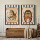 A pair of framed illustrations featuring whimsical hedgehogs hangs side-by-side on a light-colored wall above a wooden storage bench. Each piece of art is encased in a simple wood frame and features a design with vertical blue and white stripes around a central tan panel bordered by a red scalloped line. The illustration on the left shows a brown hedgehog wearing a grey flat cap and riding a vintage-style black bicycle. 