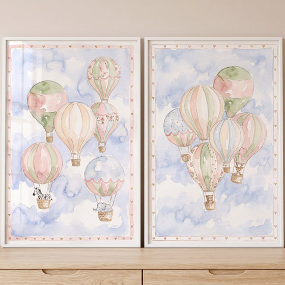 Whimsical hot air balloon wall art set of 2 features animals in baskets drifting through a soft blue watercolor sky.