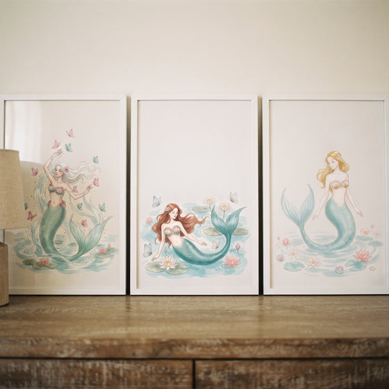 Whimsical marine watercolor mermaid wall art set of 3 framed illustrations displayed on a wooden dresser.