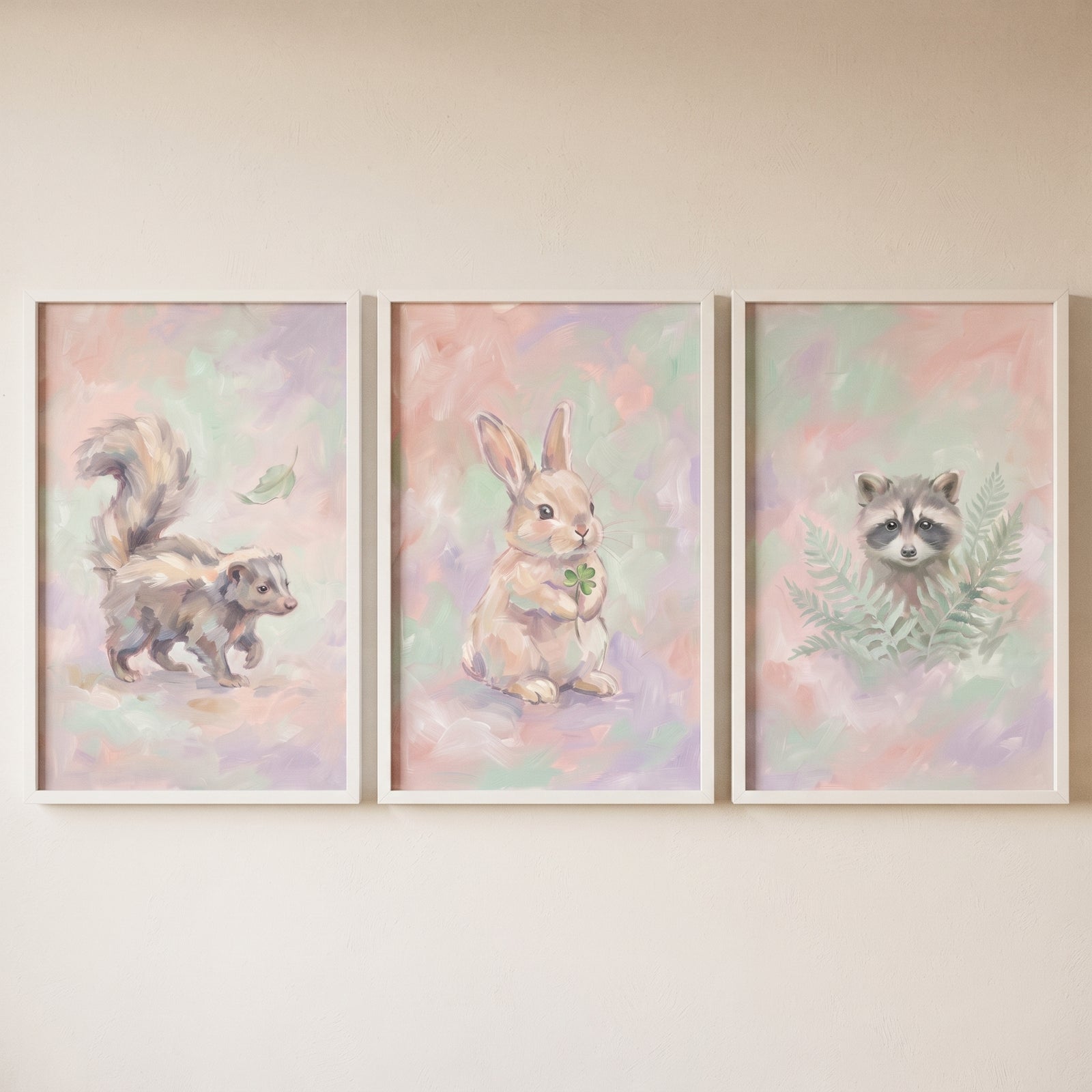 Whimsical pastel woodland animal wall art set of 3 with a skunk, rabbit with clover, and raccoon in white frames.