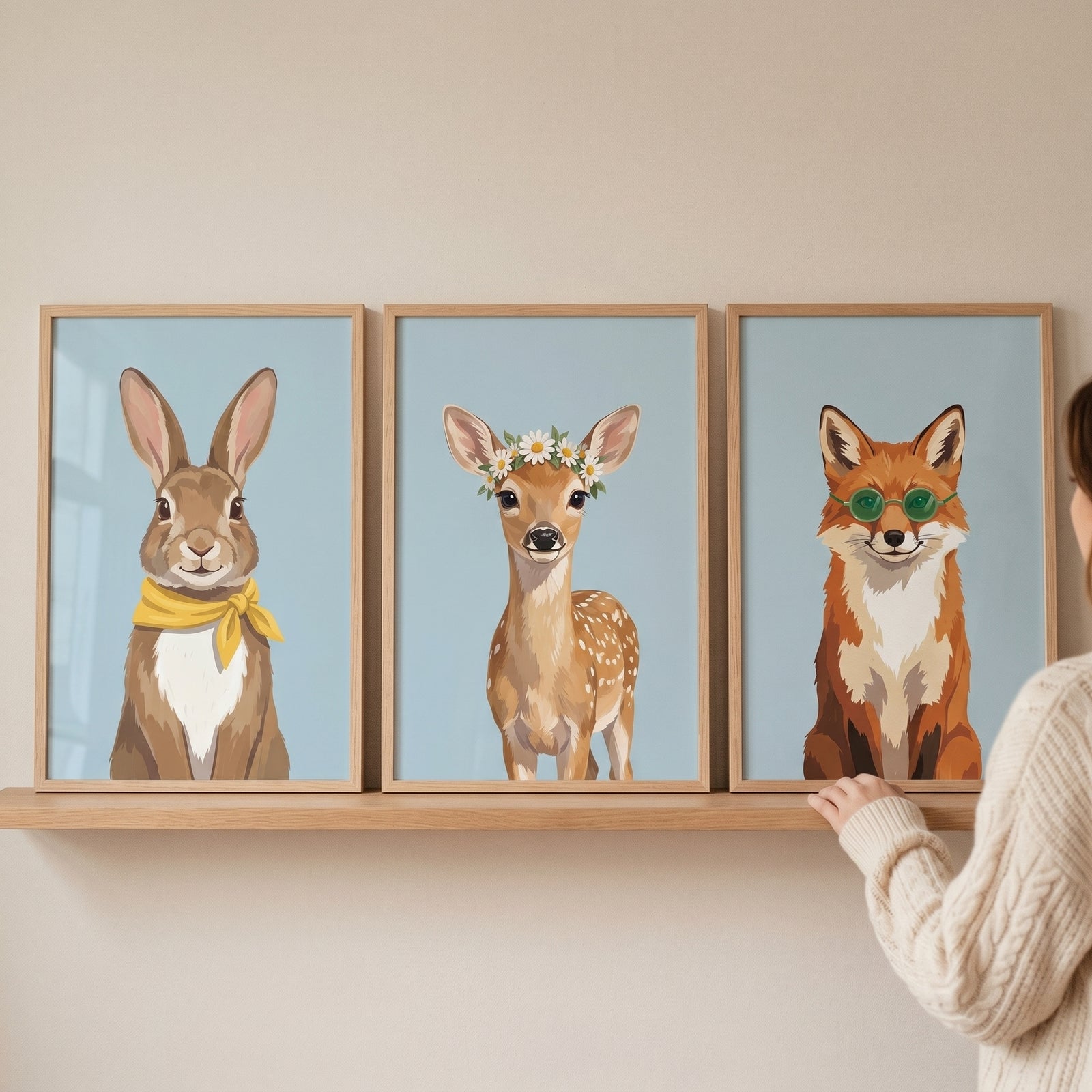 Whimsical portrait forest animal wall art set of 3 with a rabbit, deer, and fox displayed in frames on a wooden shelf.