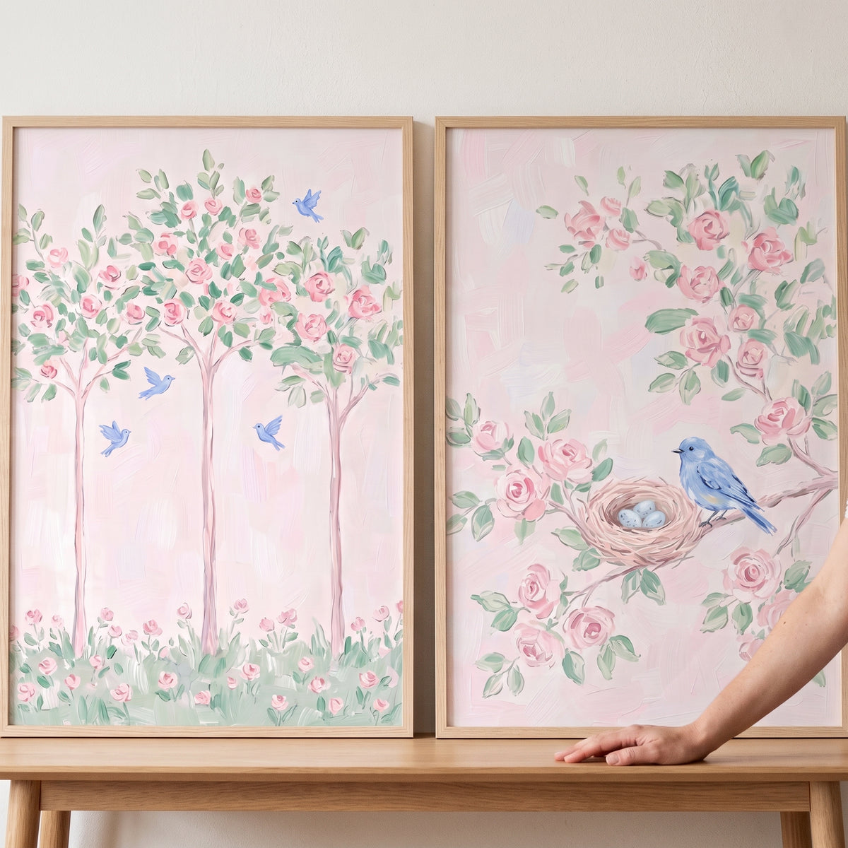 Whimsical rose blue bird wall art set of 2 features pink floral trees, birds, and a nest with eggs in light wood frames.