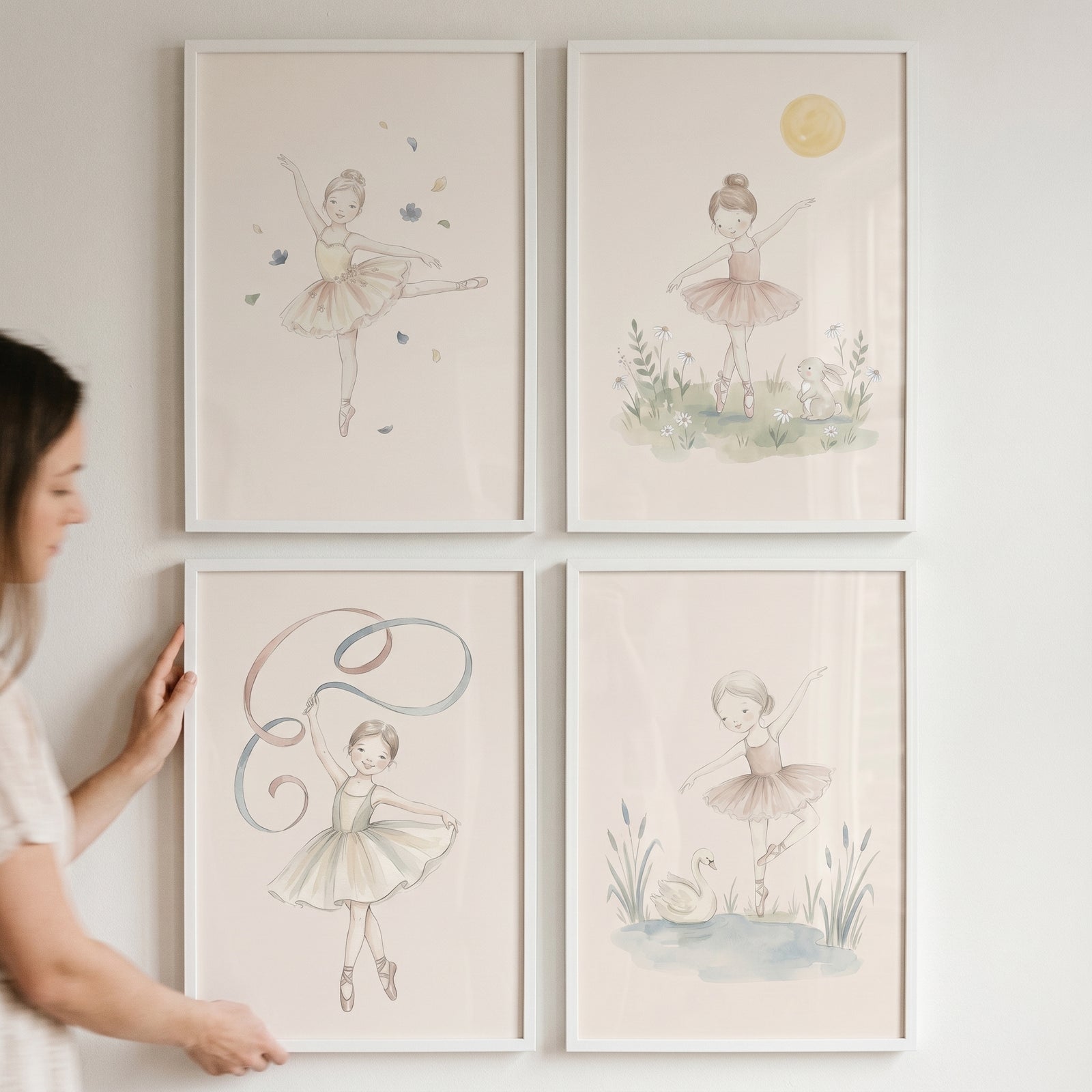 Woman holds a whimsical watercolor little ballerina wall art set of 4 featuring young dancers with animals and flowers.
