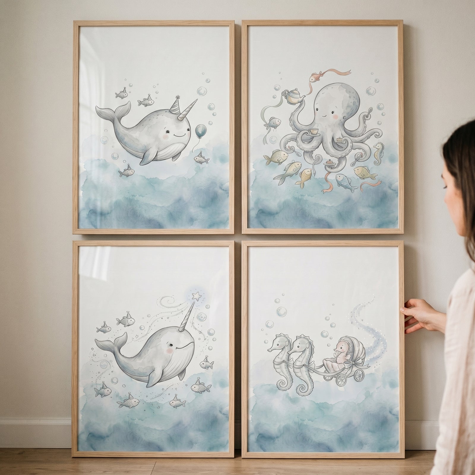 Person holds a whimsical watercolor sea animals wall art set of 4 with narwhal, octopus, and seahorse illustrations.