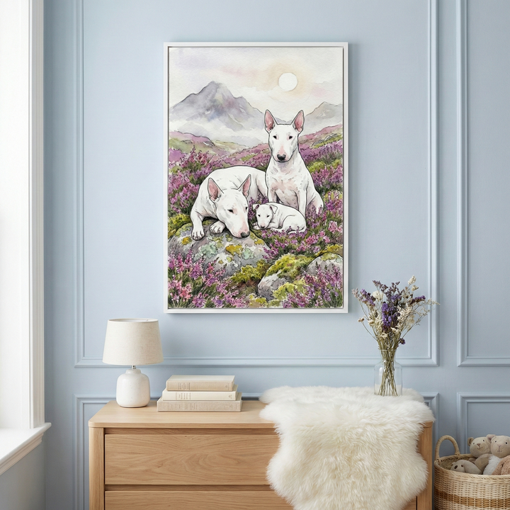 A framed piece of art on a light blue wall depicts two adult white dogs and a small puppy, characterized by their unique oval heads and pointed ears. They are resting among purple flowers and rocks with mountains under a pale sun in the background. Below the art, a light wood dresser holds a lamp, books, and a vase of dried purple flowers. A white faux-fur rug is draped over the dresser, and a wicker basket with plush toys is visible on the floor.
