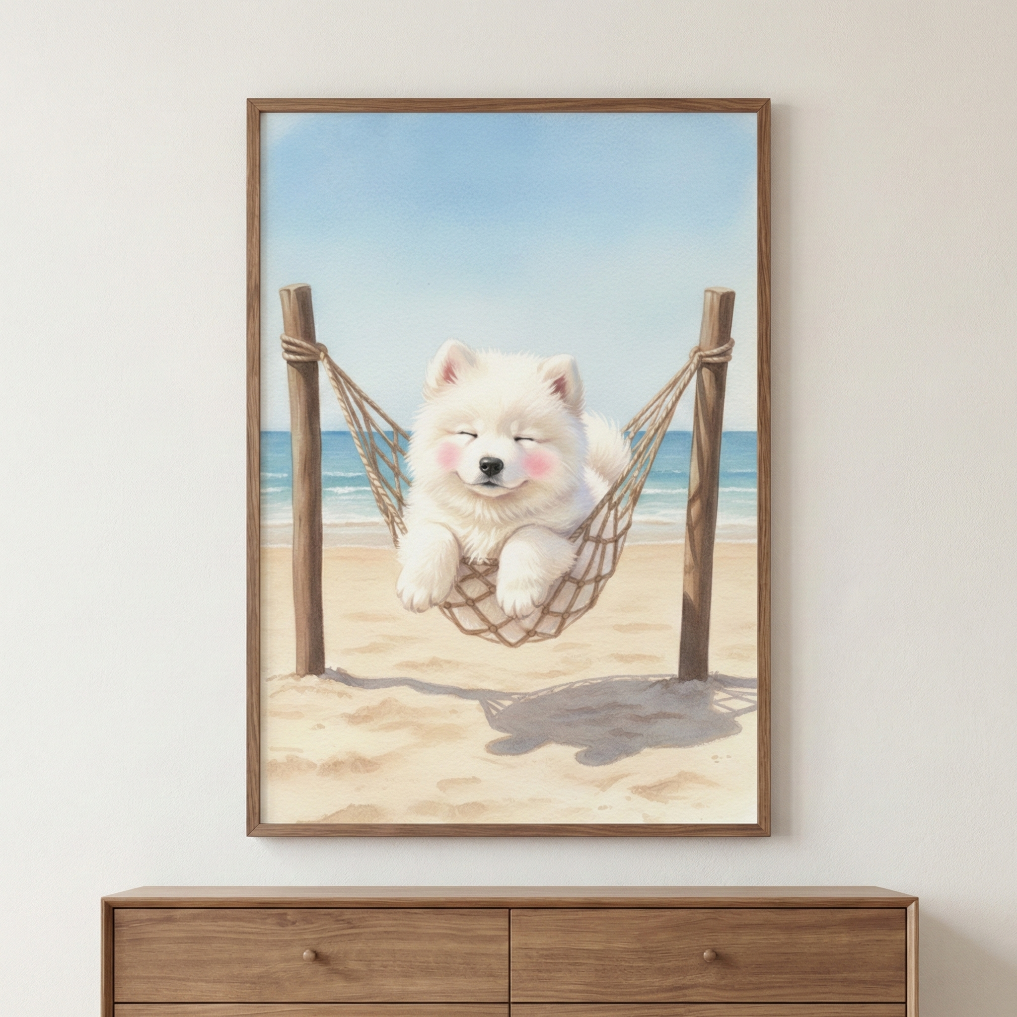 A vertical wooden frame hangs on a plain white wall, showcasing a watercolor-style illustration of a fluffy white puppy. The small dog, which has its eyes closed and rosy pink cheeks, rests comfortably inside a rope hammock. The hammock is suspended between two wooden posts anchored in the soft sand of a beach. In the background, a serene turquoise ocean meets a clear blue sky. Below the framed artwork sits a mid-toned wooden dresser with two drawers.