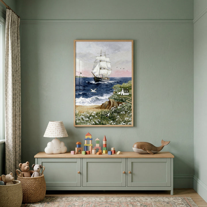 This tranquil child's room is decorated in a soft sage green. Centered on the wall is a large, framed piece of artwork depicting a classic sailing vessel with multiple white sails traveling across a deep blue sea. The scene in the frame includes a coastline with small white flowers, a sandy beach, and a quaint cottage perched atop a cliff.