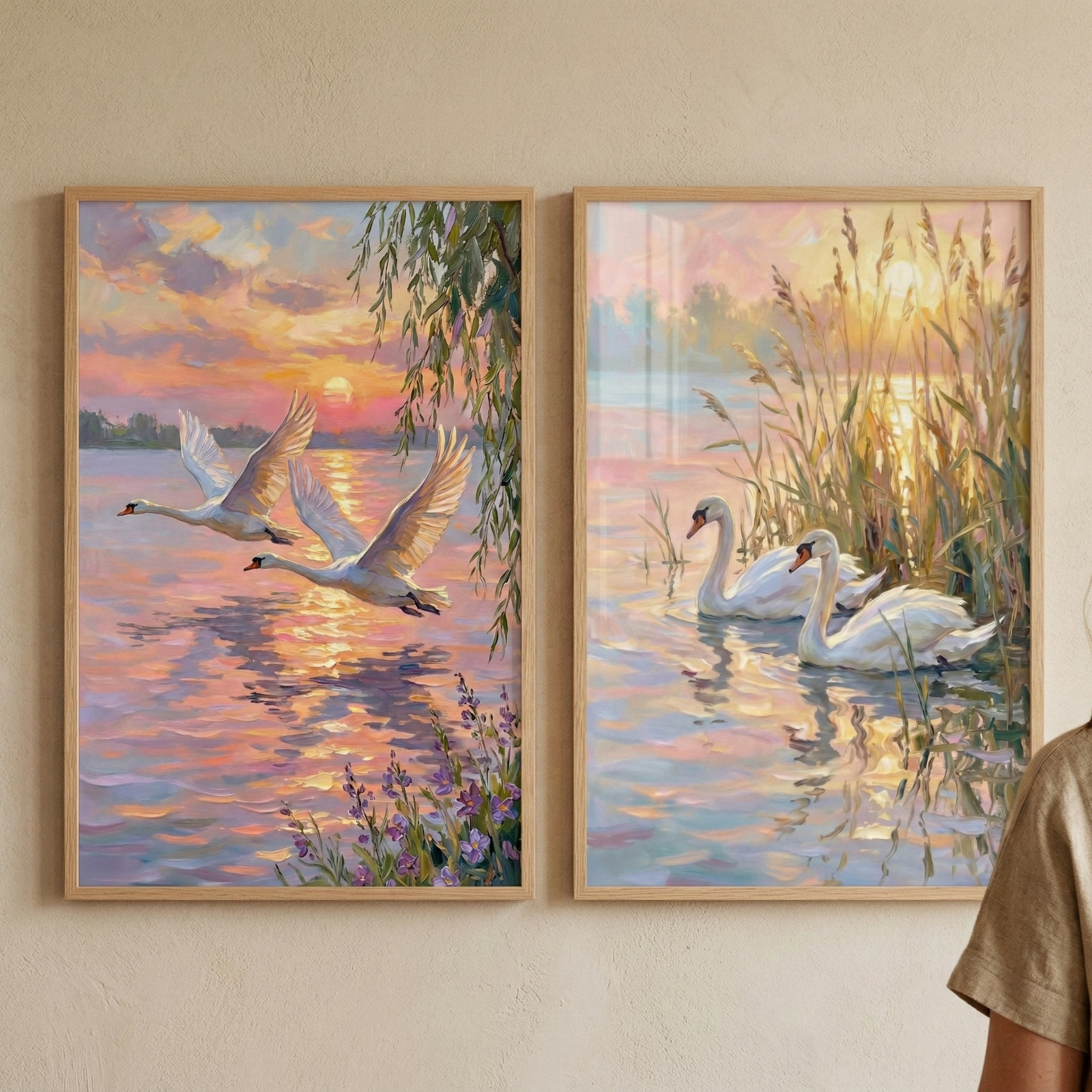 Two framed paintings of white swans at sunset displayed side by side as serene nature wall art. One artwork shows two swans flying low over glowing water while the other shows a pair swimming beside tall reeds reflecting warm evening light.