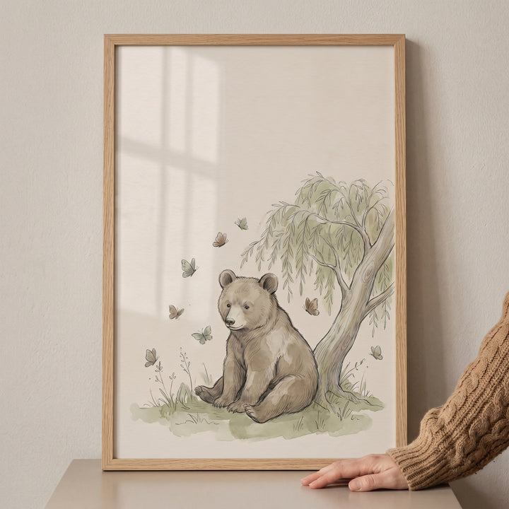 Willow tree sitting bear wall art in a light wood frame features a bear cub, butterflies, and soft green foliage.