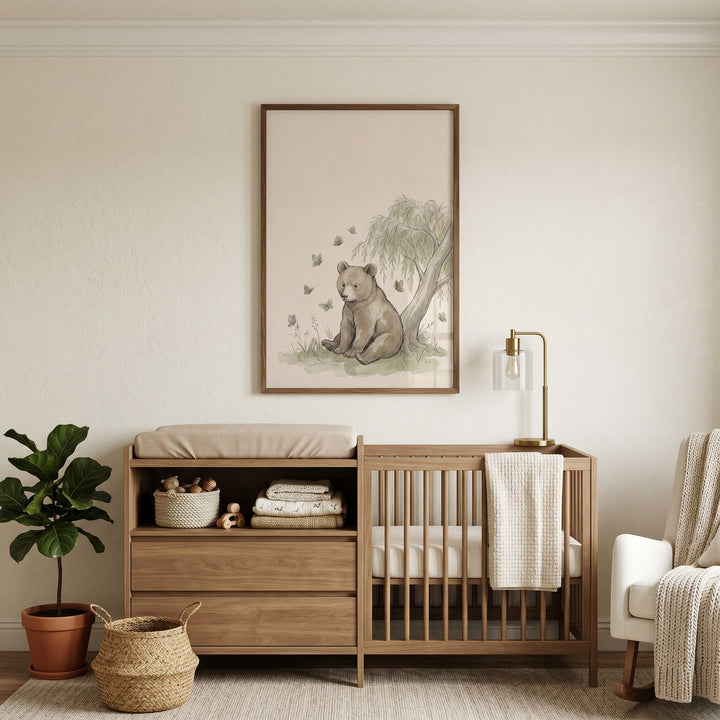 Neutral nursery featuring a wooden crib, changing table, and willow tree sitting bear wall art on a beige wall.