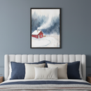 Bedroom with a white upholstered bed and blue and cream pillows. A framed watercolor painting of a red cabin in a snowy forest with smoke from the chimney hangs centered above the bed.