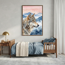 A brightly lit child's bedroom features a large, vertically oriented framed artwork hanging on a neutral-toned wall. The illustration inside the frame shows a wolf in profile, rendered in soft watercolor styles. Behind the animal are layers of misty blue mountains and a pale pink sky where a small flock of birds is visible. Below the artwork sits a wooden toddler bed with a side rail, dressed in light blue linens and a textured off-white knit blanket. 