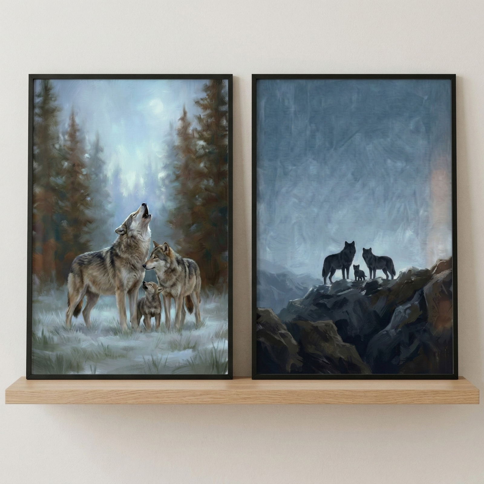 Two framed wolf paintings lean on a light wood shelf against a plain wall. The left painting shows two adult wolves and a pup in a misty forest with one wolf howling, while the right painting shows three wolves standing on dark rocks beneath a cloudy blue gray sky.