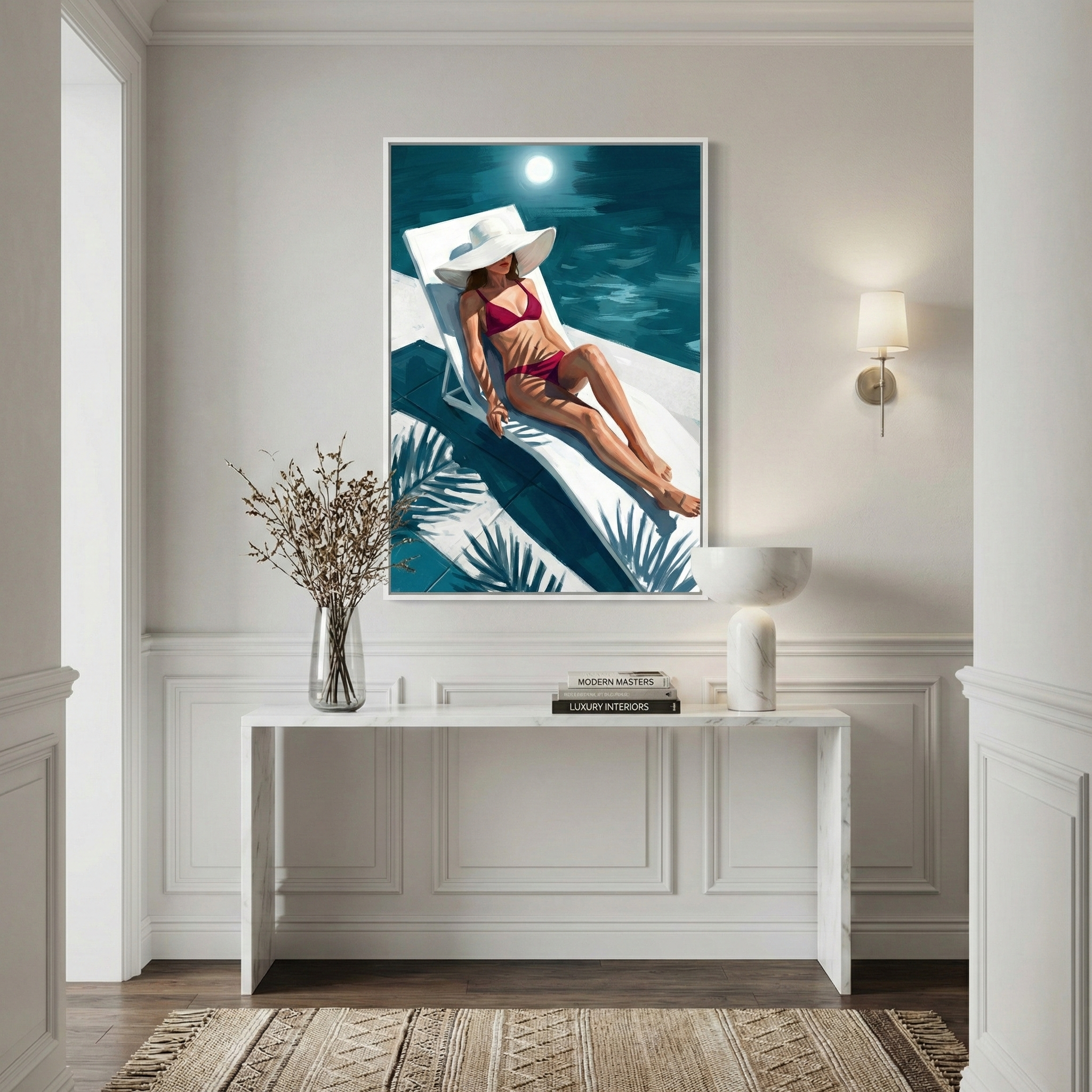 An elegant interior entryway featuring a minimalist white console table against a sophisticated paneled wall. Centered above the table is a large, vertical framed illustration. The artwork depicts a woman in a vibrant red swimsuit and a wide-brimmed white sun hat reclining on a white chaise longue. The scene is set by a pool at night, illuminated by a glowing moon, with deep teal water and dark palm leaf shadows cast across the foreground. 

