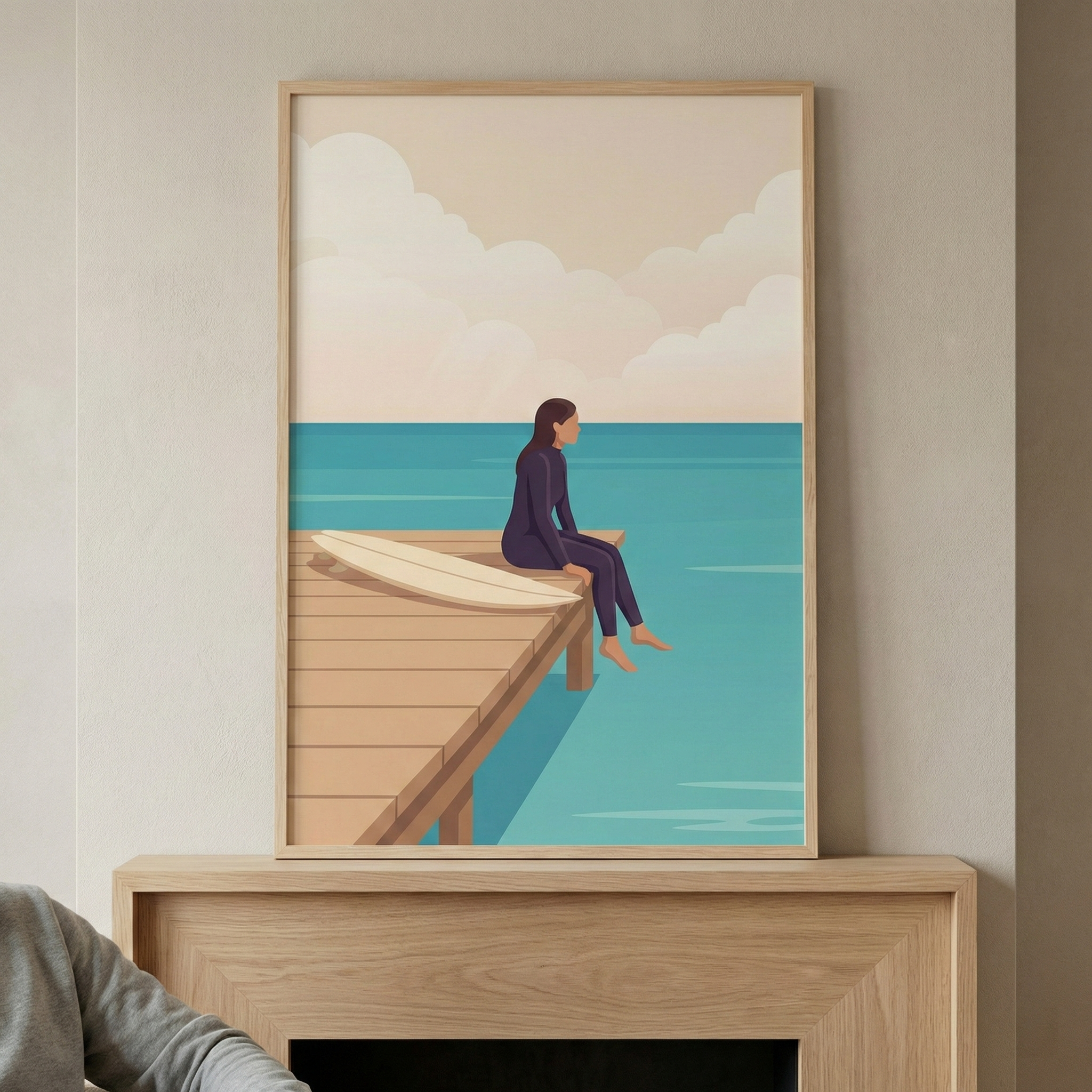 A minimalist digital illustration depicts a person in a dark purple wetsuit sitting on the edge of a wooden dock, looking out at a turquoise ocean. A white surfboard rests on the pier beside them. The background features a soft-colored sky with stylized, rounded clouds in shades of cream and light pink. The framed artwork hangs on a neutral wall above a light wood mantle, showcasing a calm and peaceful coastal scene in a flat, modern style.