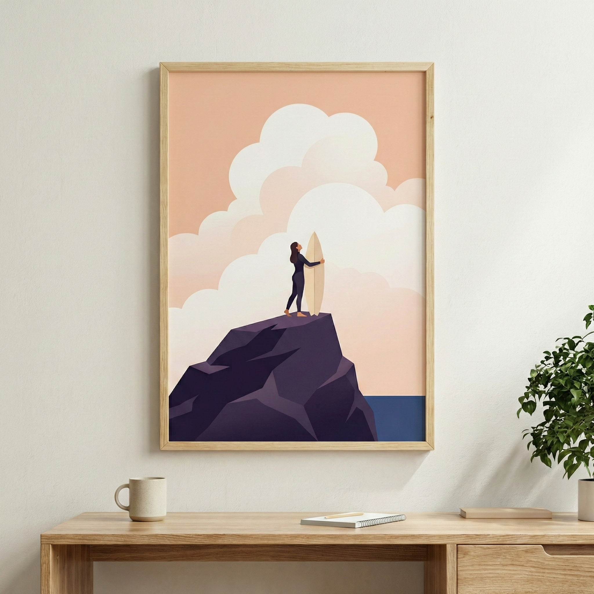 A vertical digital illustration in a minimalist, flat graphic style is shown in a light wood frame hanging on a pale wall. The artwork depicts a female figure in a dark wetsuit standing at the peak of a large, dark purple rocky formation. She is holding a light-colored surfboard vertically beside her. The background consists of a soft peach-colored sky filled with large, stylized, rounded white clouds. A small portion of a dark blue ocean is visible on the right side of the horizon. 
