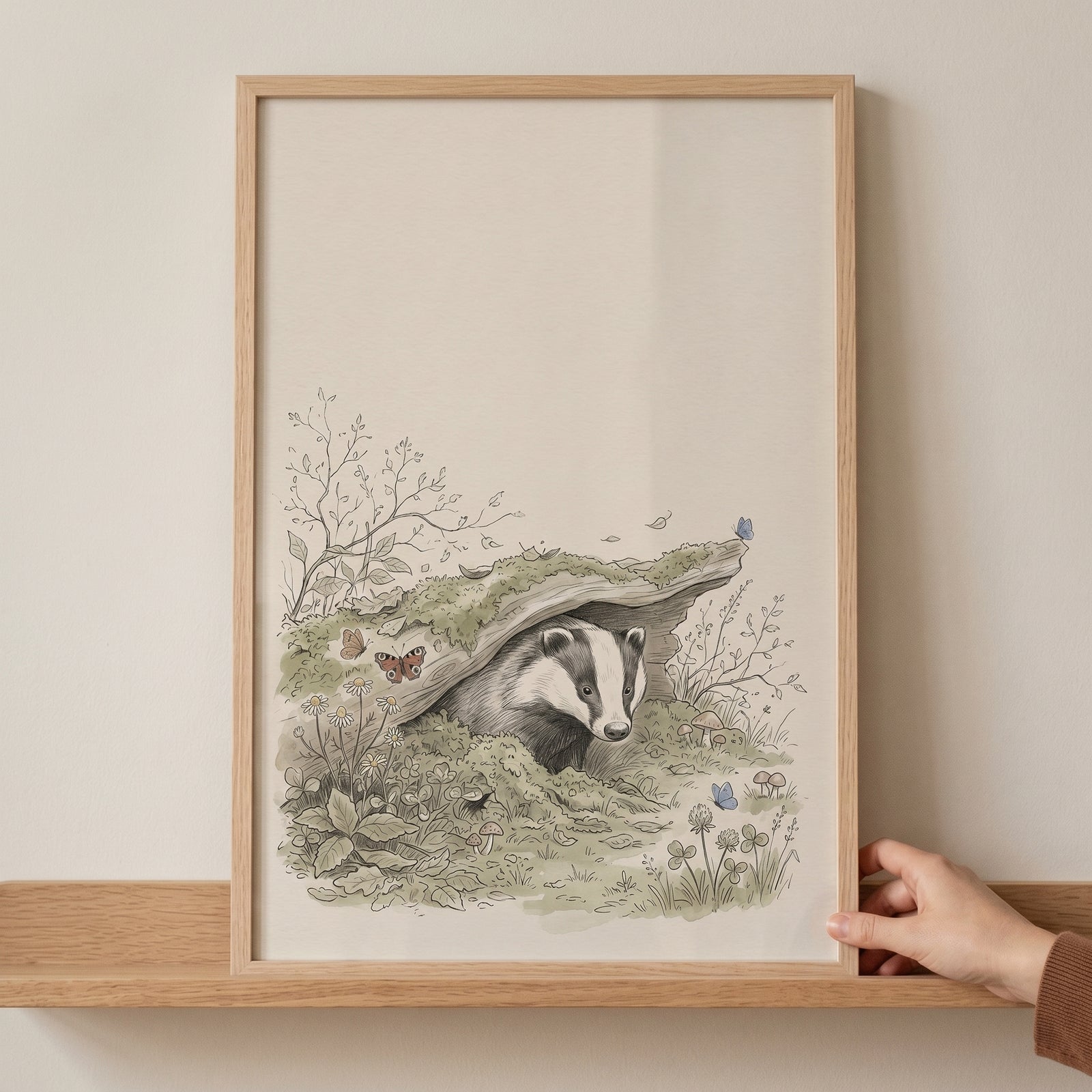 Framed woodland mossy den badger wall art showing a badger peeking from its hollow log home amidst forest plants.