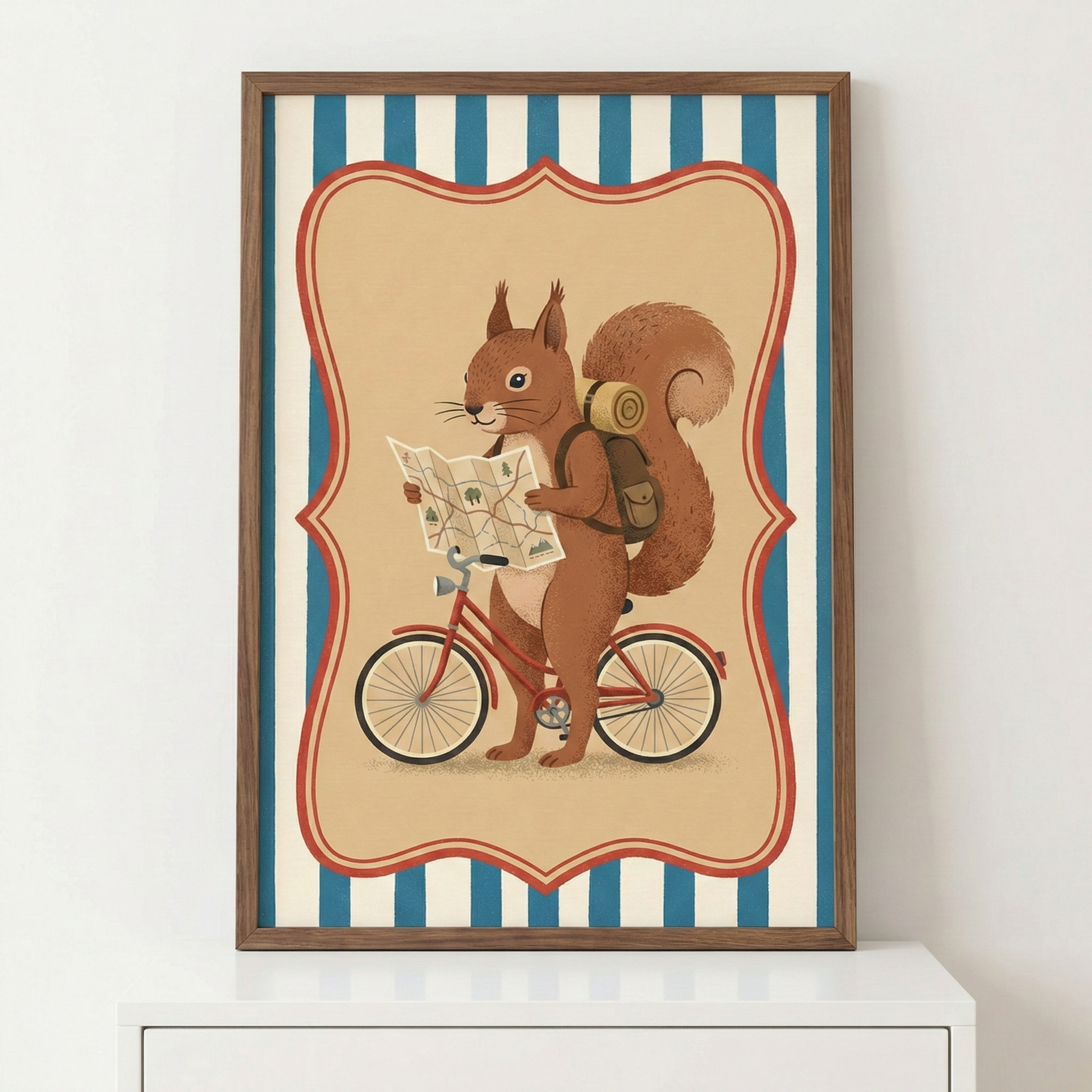 A framed illustration of a brown squirrel holding a map and standing next to a red bicycle. The squirrel wears a backpack with a rolled-up mat on top, appearing ready for a journey. The central artwork is enclosed in an ornate red decorative border on a beige background, which is set against a pattern of vertical blue and cream stripes. The piece is displayed in a wooden frame sitting on a white surface.