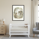 Modern nursery with a white crib, wooden dresser, and gray armchair. A large framed watercolor print of a boy in an adventurer outfit touching a wolf's nose in a forest hangs above the crib.