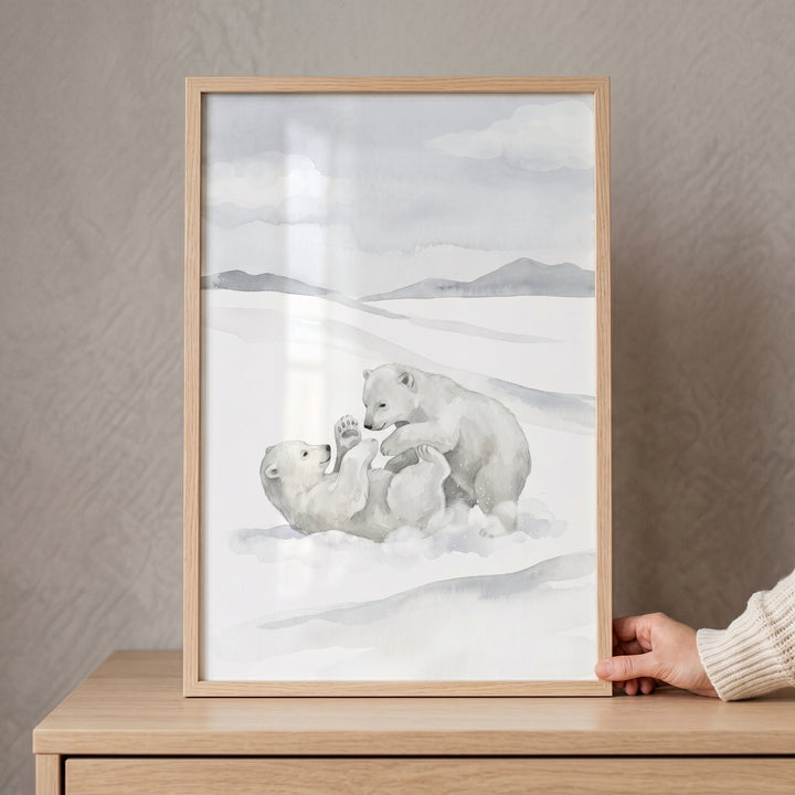 Wrestling snowy polar bear wall art featuring two bear cubs playing, framed on a wooden dresser and held by a hand.