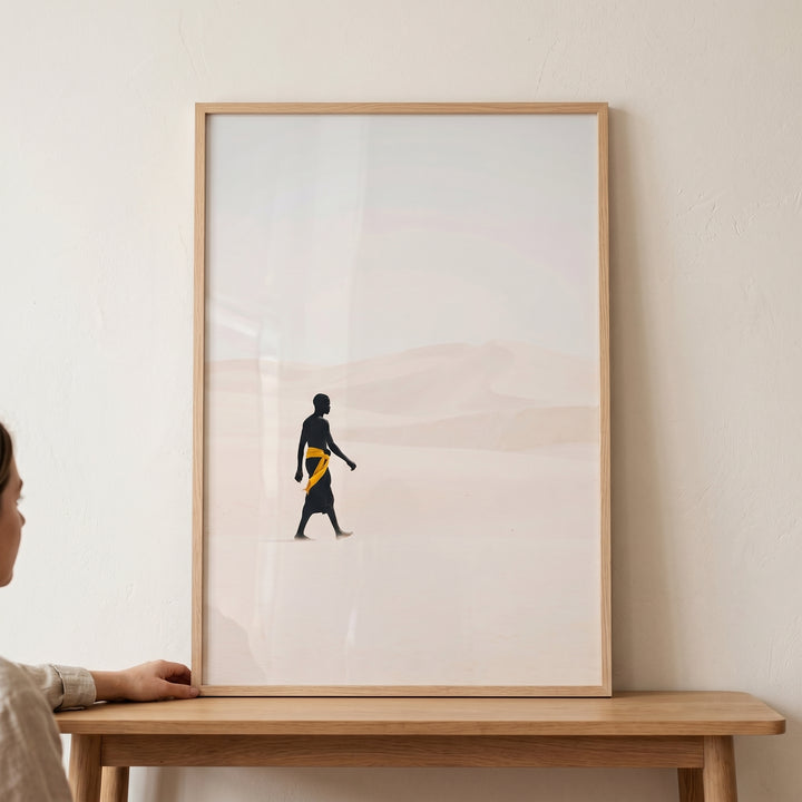 Yellow sash walking man wall art shows a silhouette traversing a minimalist desert landscape with soft beige dunes.