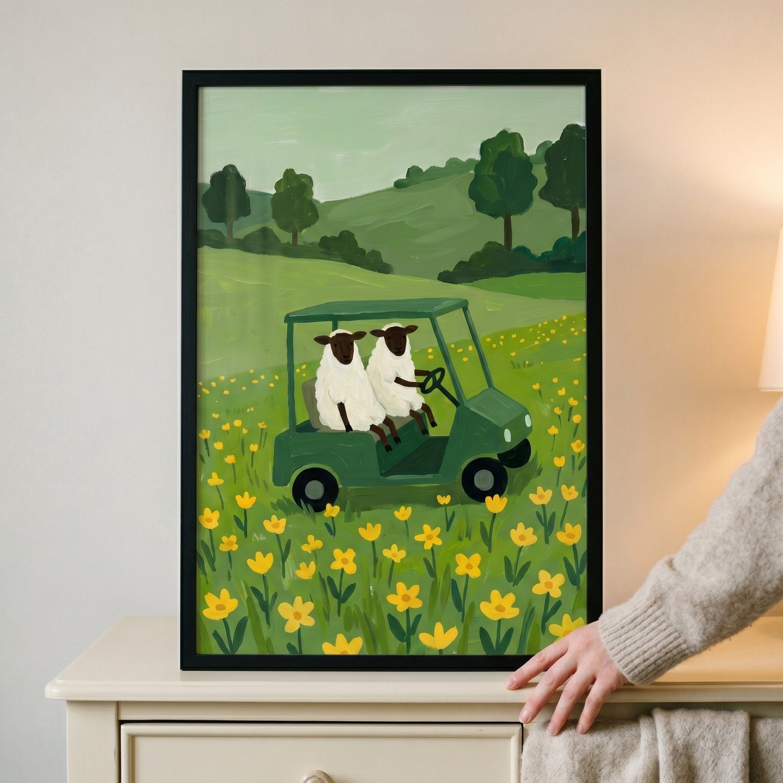 Yellow wildflower driving sheep wall art features two sheep in a green cart in a field of yellow flowers and green hills.