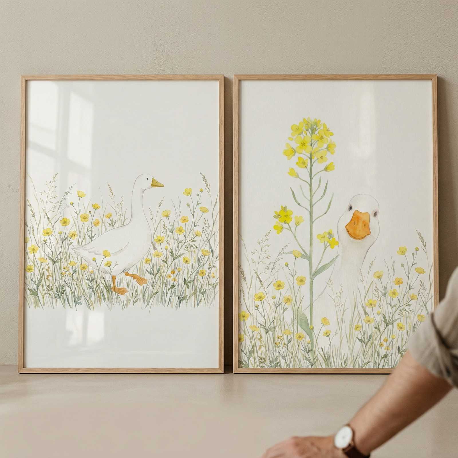 Two framed watercolor prints show white ducks among soft yellow wildflowers one walking through a meadow and the other peeking beside a tall yellow bloom. The light wood frames and gentle botanical details create a calm nature inspired nursery wall display.