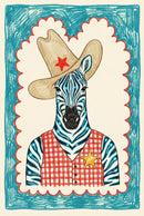 A colorful framed illustration of a zebra wearing a tan cowboy hat with a red star and a red checkered sheriff's vest is displayed in a bright nursery setting. The room includes a light wood crib with a blue blanket, a plush teddy bear on a jute rug, and a small stool with stacked books.